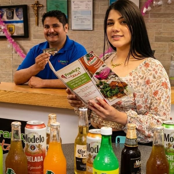 Two Franky's Tacos employees, one holding a menu and the other a business card, with drinks.